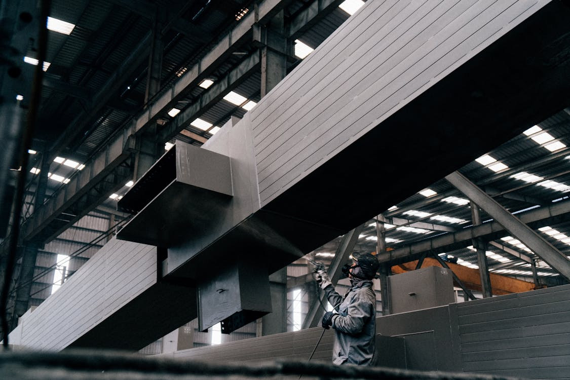 Free photo of man in worker suit spraying on metal structure